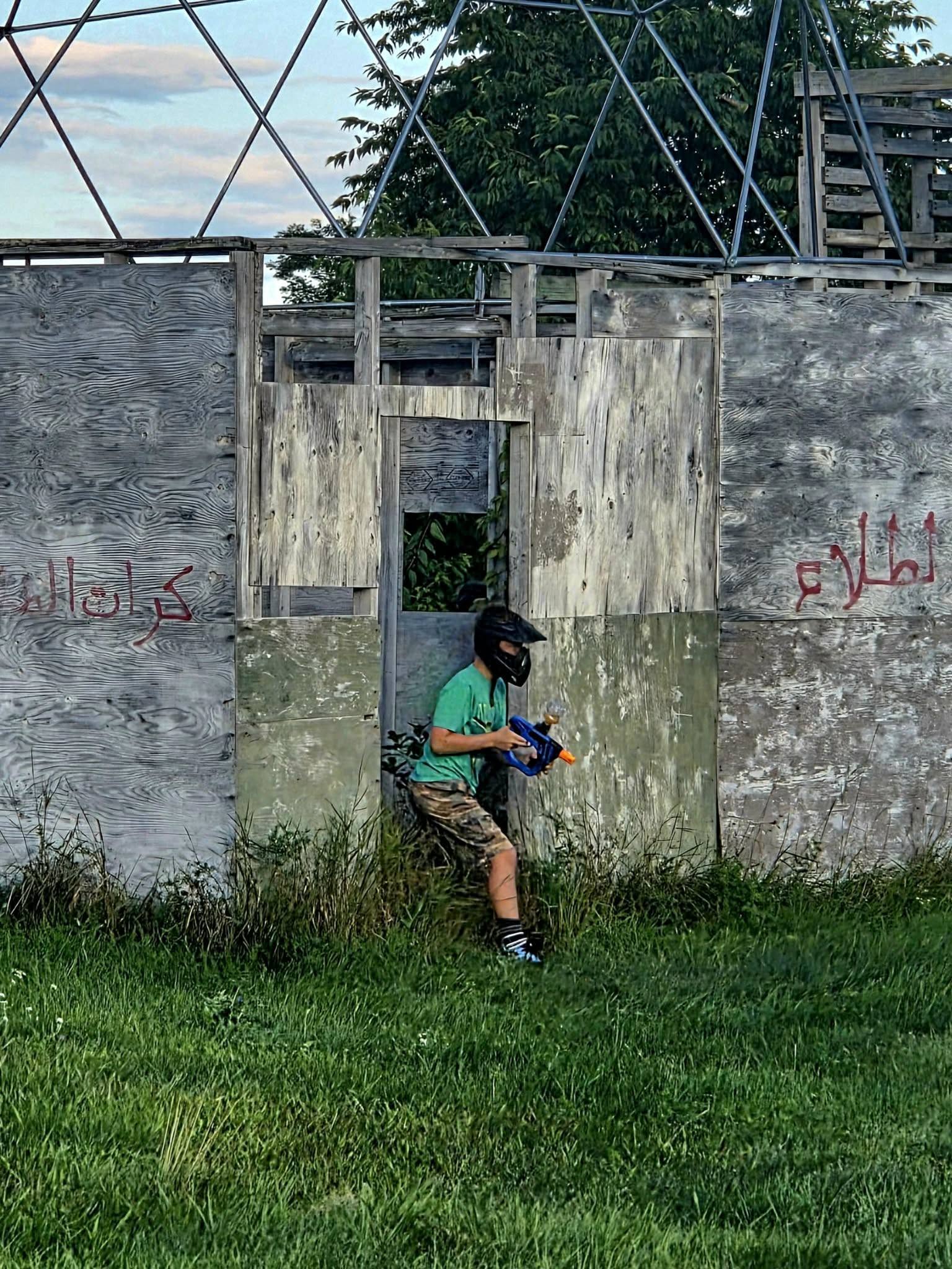 Young player in protective gear moving beside a field building